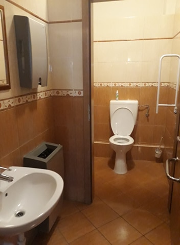 A WC két helyiségből áll, az elsőben baloldalt található a kézmosó, innen nyílik a félig akadálymentesnek mondható WC.