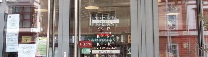 A bejárat az utcáról, fém keretes üvegajtókkal,melynek jobb szárnya kifelé nyílik, nem automata.
