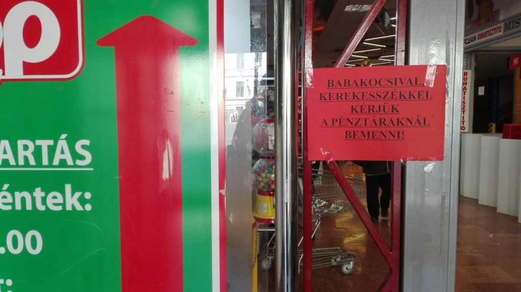 A Coop élelmiszerbolt pénztárnál felirat: babakocsival és kerekesszékkel kérjük a pénztáraknál bemenni!
