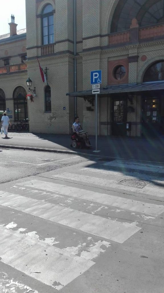 A vasútállomás főbejáratához vezető zebra mellett tábla jelzi az egy darab akadálymentes parkolót.