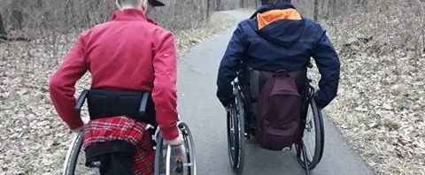 A bicikliúton két kerekesszékes srác gurul egymás mellett őszi levelek között. Torsten és Gergő az.