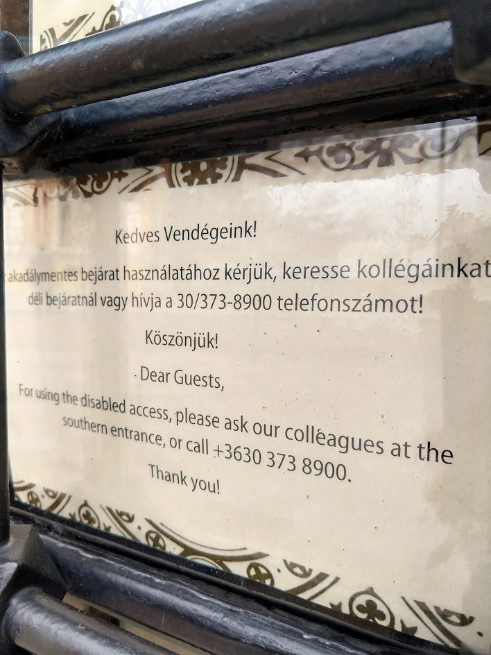 Kérésünkre tábla került ki a zárva tartó akadálymentes bejárathoz, a felirat arról tájékoztat, hogy a bejárat használatához keressék a Dzsámi kollégáját, a 30/3738900 telefonszámon.