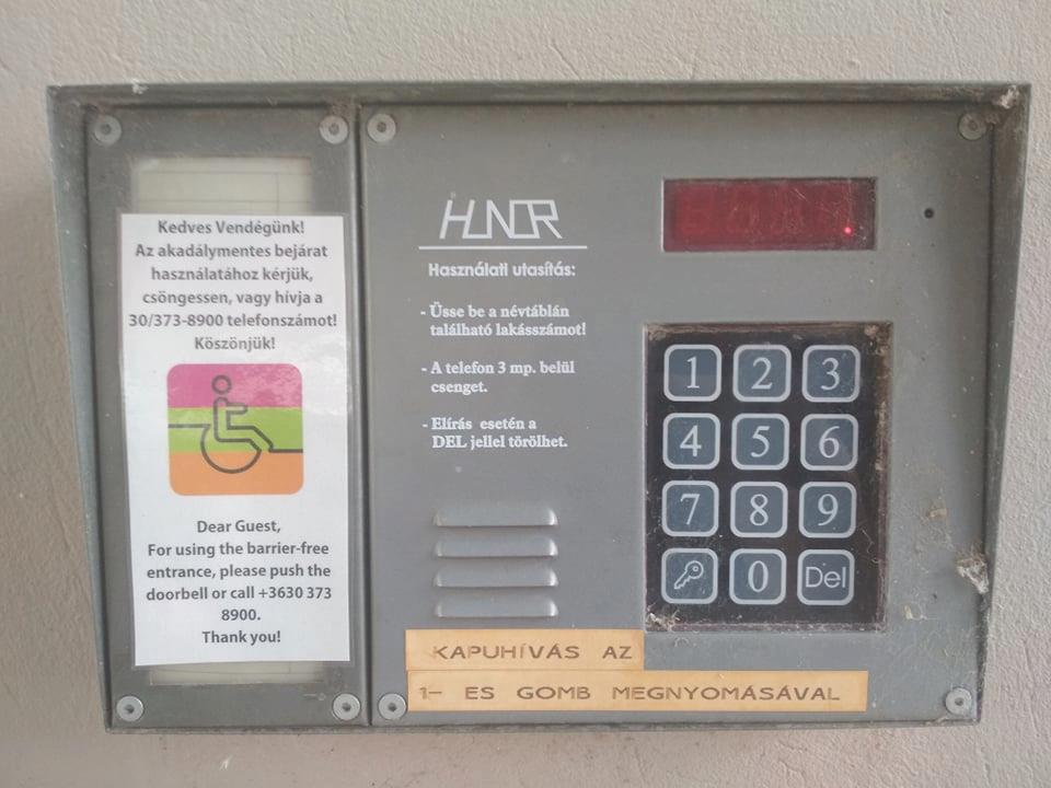 A képen a Magtár Látogatóközpont kaputelefonja látható. Klasszikus fémből készült ledes kijelzős berendezés a névtáblák helyén a következő felirattal: Kedves Vendégünk! Az a kadálymentes bejárat használatához kérjük csöngessen, vagy hívja a 30/373-8900 telefonszámot! Köszönjük!