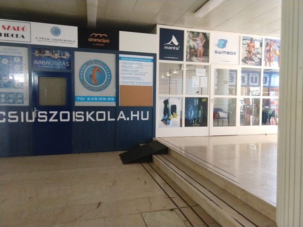 A hullámfürdő egyik helysége. velünk szemben egy nagy fal, rajta reklám plakátok. Található egy kisebb lépcső, aminek végén van egy fekete rámpa.
