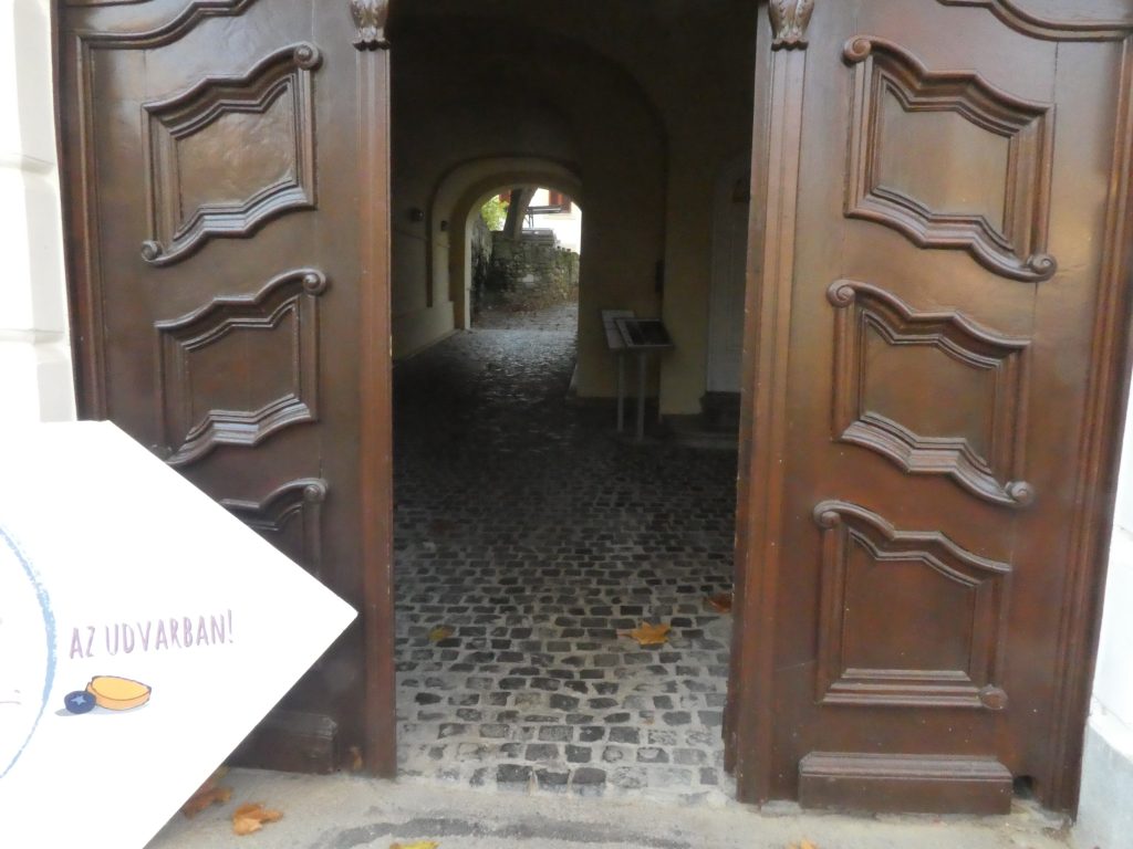 A Szent István tér felőli bejárati kapu közelről fotózva. Itt látszik, hogy a kapulajba belépve kis macskaköves borítású az út, szemben a kertbe vezető szintén boltíves kijáratot látjuk.