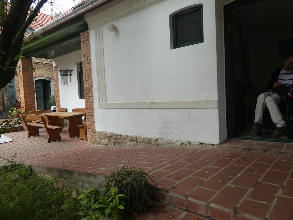 Az akadálymentes apartmanhoz vezető, téglából kirakott, sima, kis lejtésszögű rámpát látjuk.