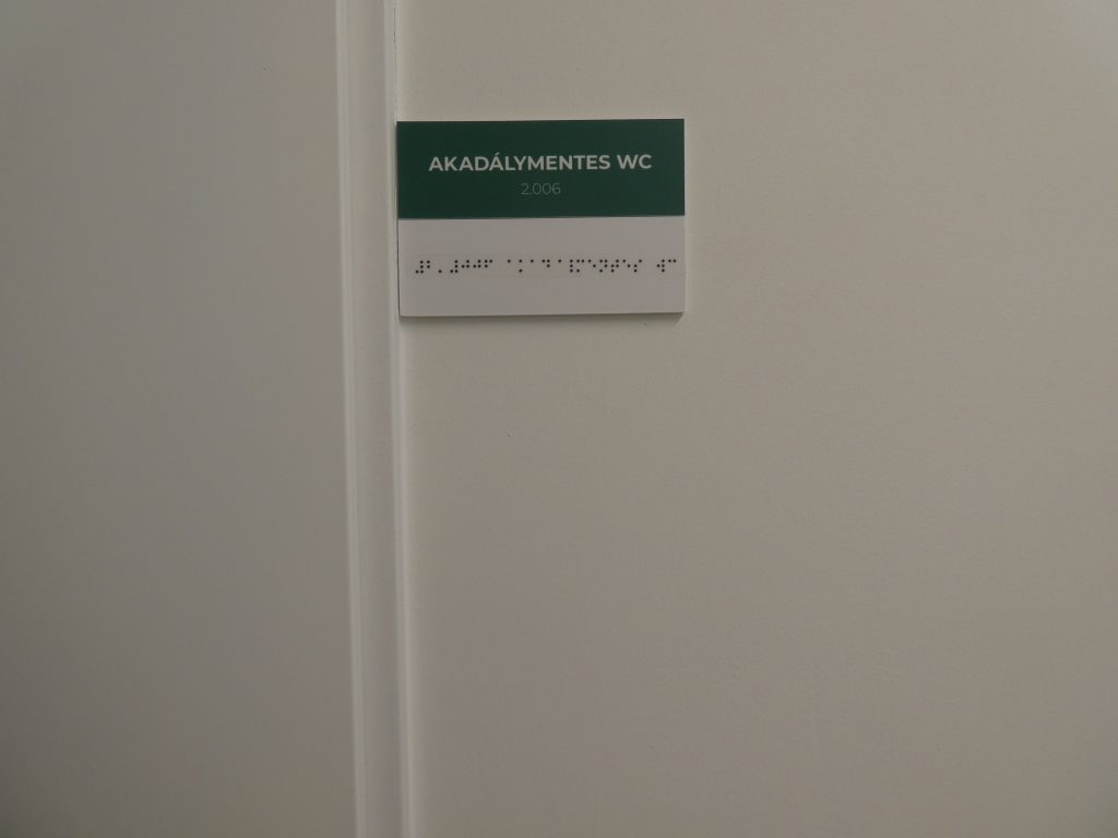 Vásárcsarnok akadálymentes WC Braille felirattal