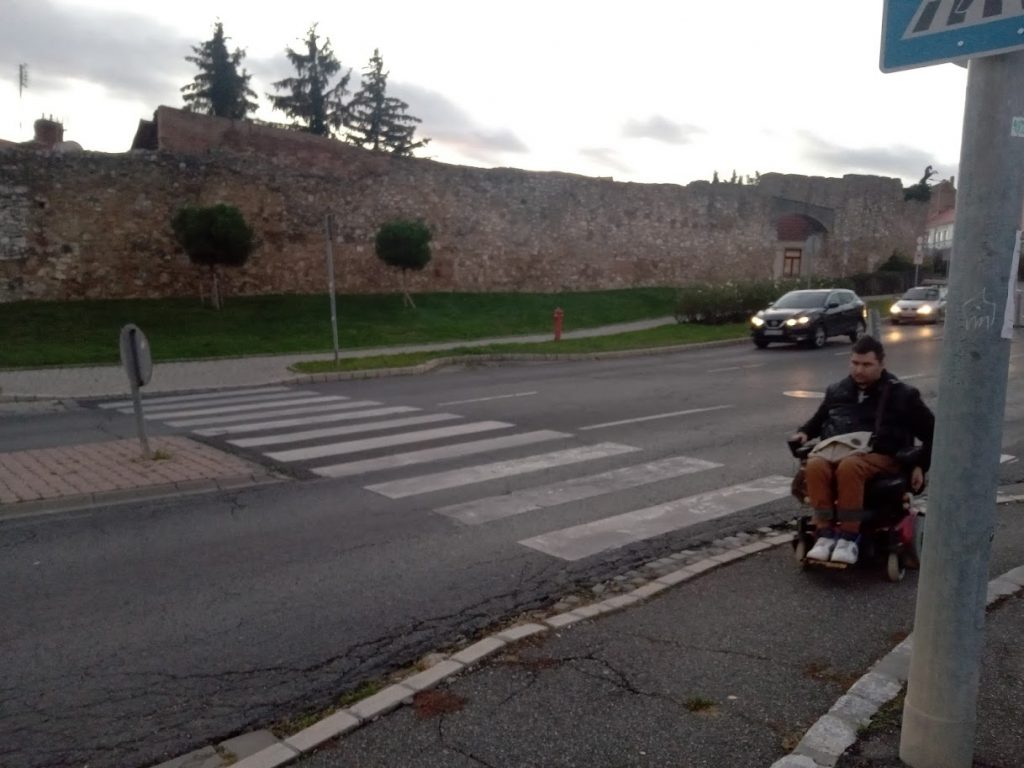 A zebra átkelőnél áll Roland kerekesszékkel. Az átkelőnél sincsen padka, vagyis akadálymentes kerekesszékeseknek.