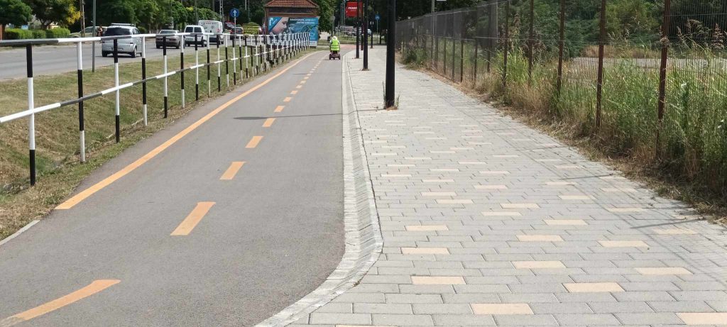 A járdákat látjuk. Itt külön közlekedési lehetőség kerekesszéknek, babakocsinak, vagy biciklinek. Mellette kissé magasabban a gyalogosoknak. A gyalogos rész sima térkő burkolat.