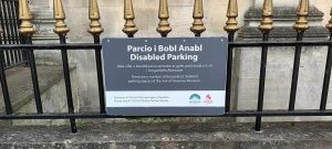 Régi kovácsoltvas korláton angol és welsh felirat arról hol parkolhatnak a fogyatékossággal élő látogatók a múzeum mellett.