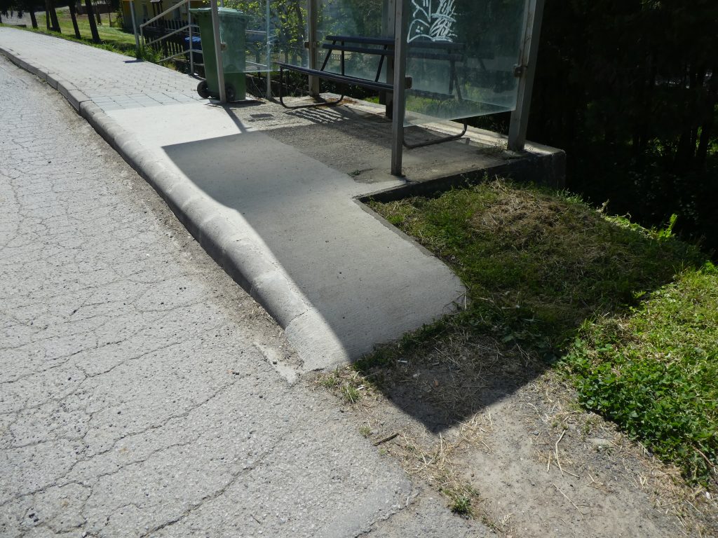 A tekeresi buszmegálló rámpája közelről. Sima, betonos rámpa, nem túl széles, de kerekesszékkel használható. 