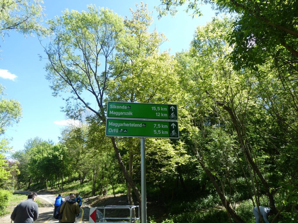 Egy táblát látunk a bicikliút mellett: Sikonda 15.5 km, Magyarszék 12 km, Magyarhertelend 7,5 km, Orfű 5,5 km.