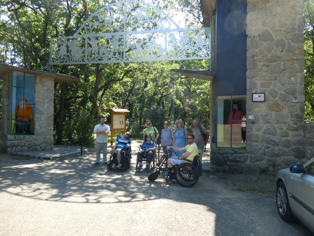 A csapat kész belépni a mesébe. A kapuban állunk 8-an, mellettünk az oszlopokban nagyméretű mesehősök bábui láthatóak. A kapu két oldalt kőből készült oszlop, az egykori vidámpark pénztárai. Ezeken ível át egy fém rács , Meseerdő felirattal.