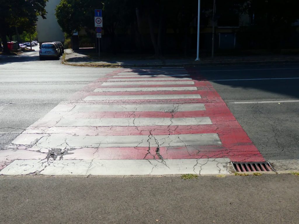 A Tüzér utca felől érkezve feltűnő színnel kiemelt, sima zebrát találunk. 