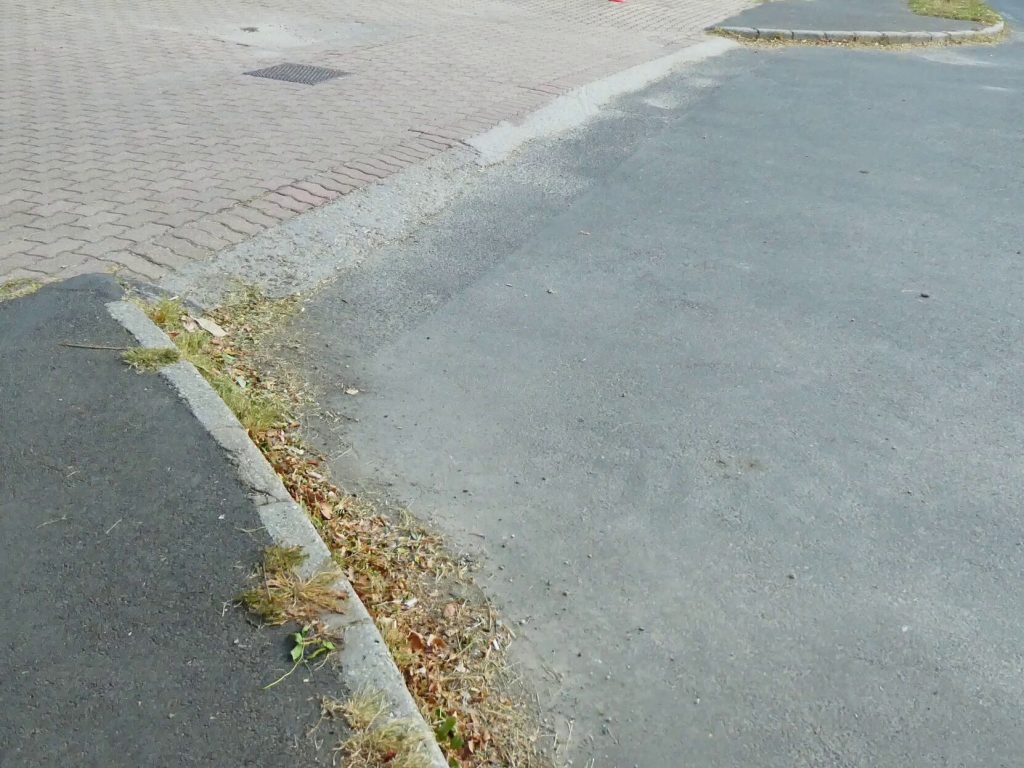 A Tüzér utca felől a járdát látjuk. A járdaszélek nem lekerekítettek, eltérő színnel sincsen jelzés. 