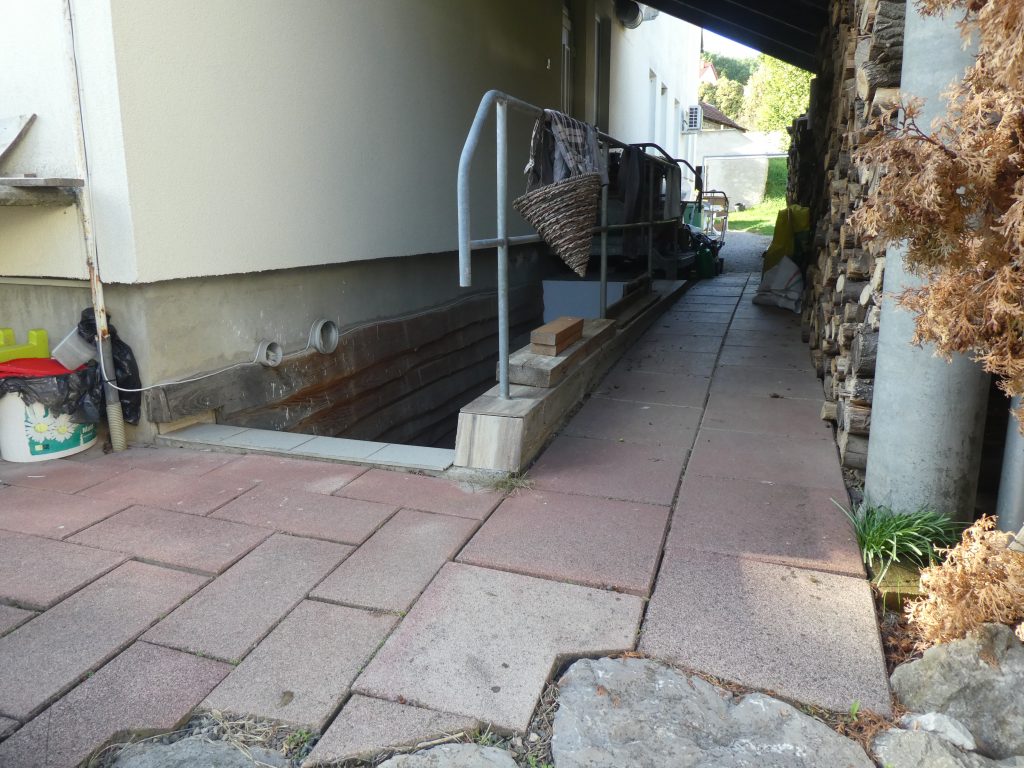 Az akadálymentes megközelítési lehetőség. Körben a felső parkolóból a terasz felé. A hátsó szakasz már sima kő burkolatú.